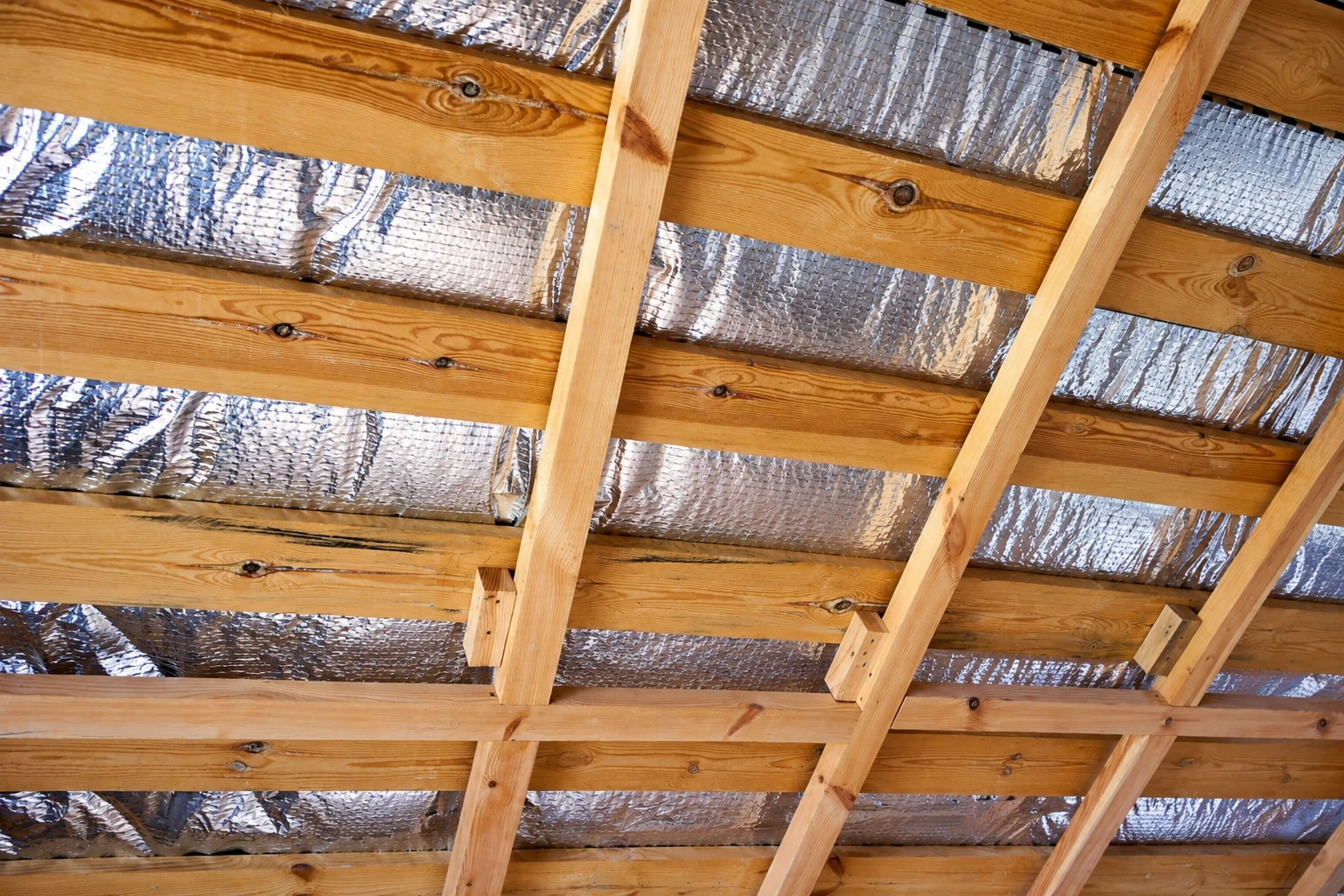 Reflective foil insulation is fitted between exposed wooden rafters.